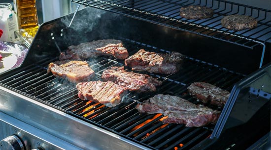 Barbecue on lit gas grill in backyard